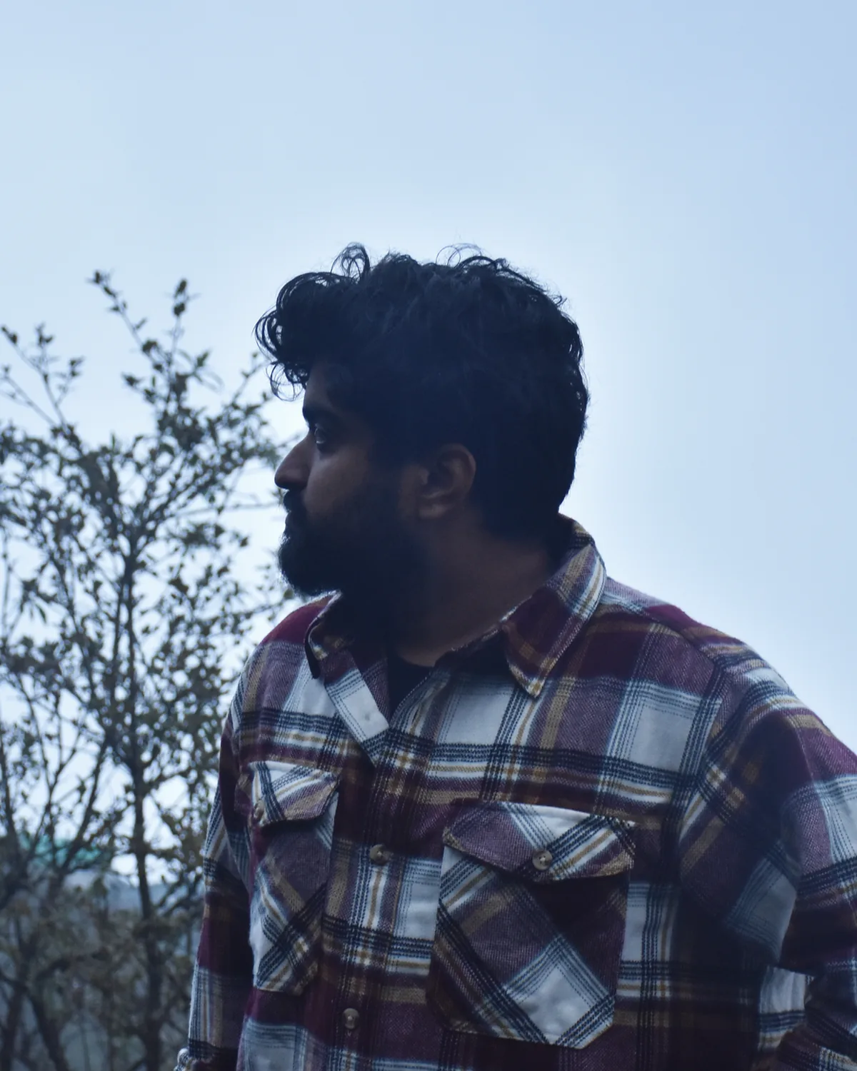 Saptarshi Chattopadhyay in a plaid shirt on a misty hillside, looking to the left